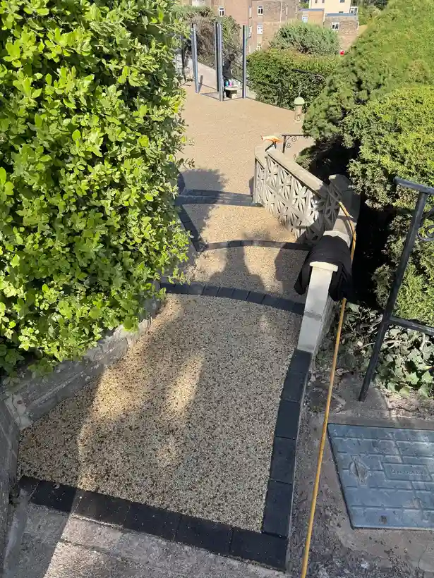 Buff resin bound pathway with black block-paving border in a Bournemouth garden