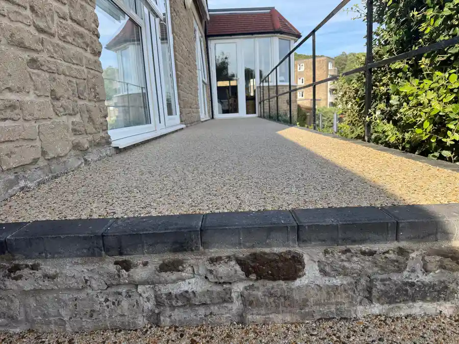 Buff resin bound garden pathway alongside a stone home in Bournemouth