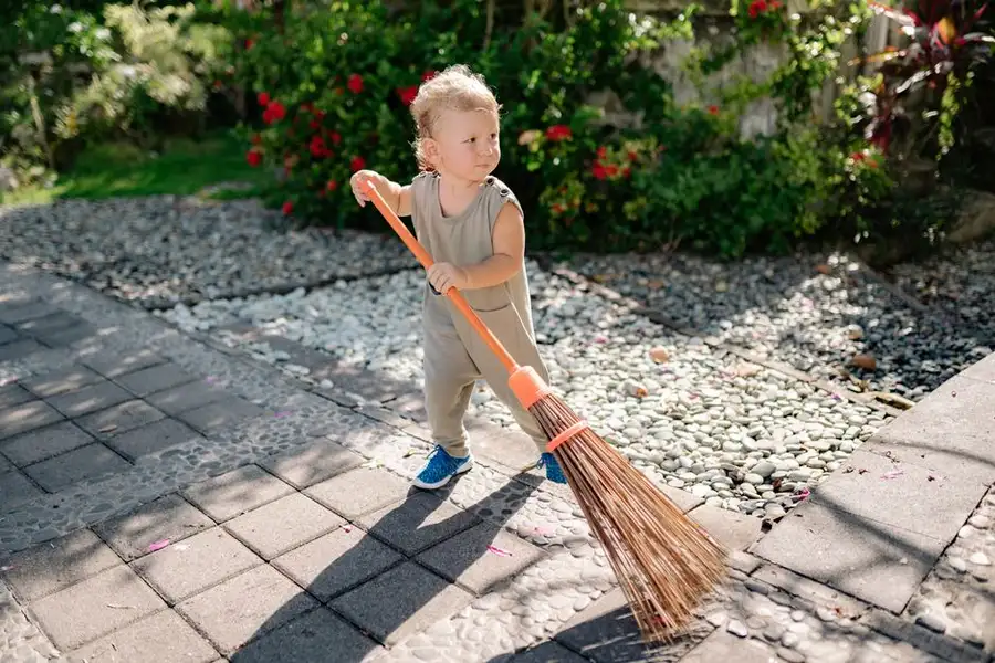 A brush sweeping a path outdoors - simple tasks done regularly keep a resin driveway looking right for years