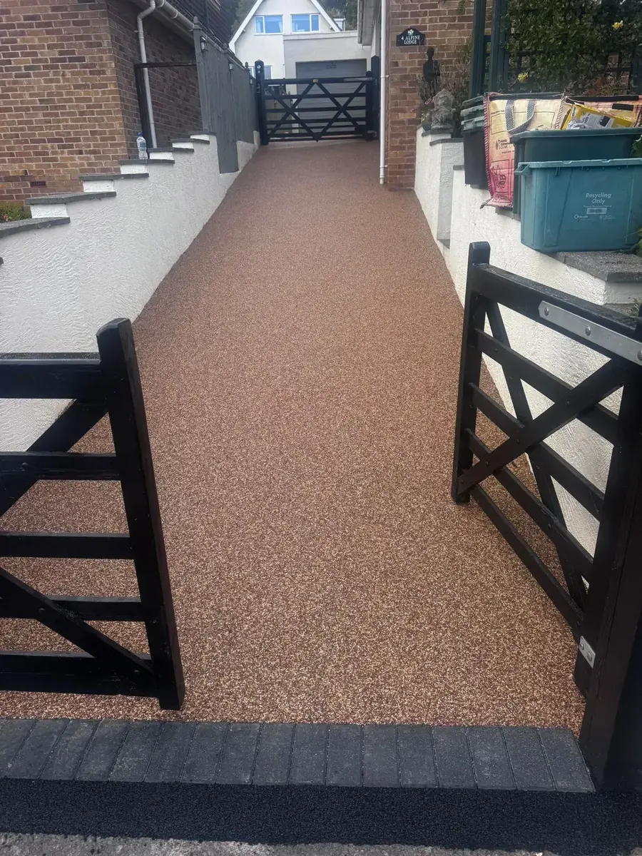 Warm brown resin bound pathway between dark wooden gates at a Bournemouth property