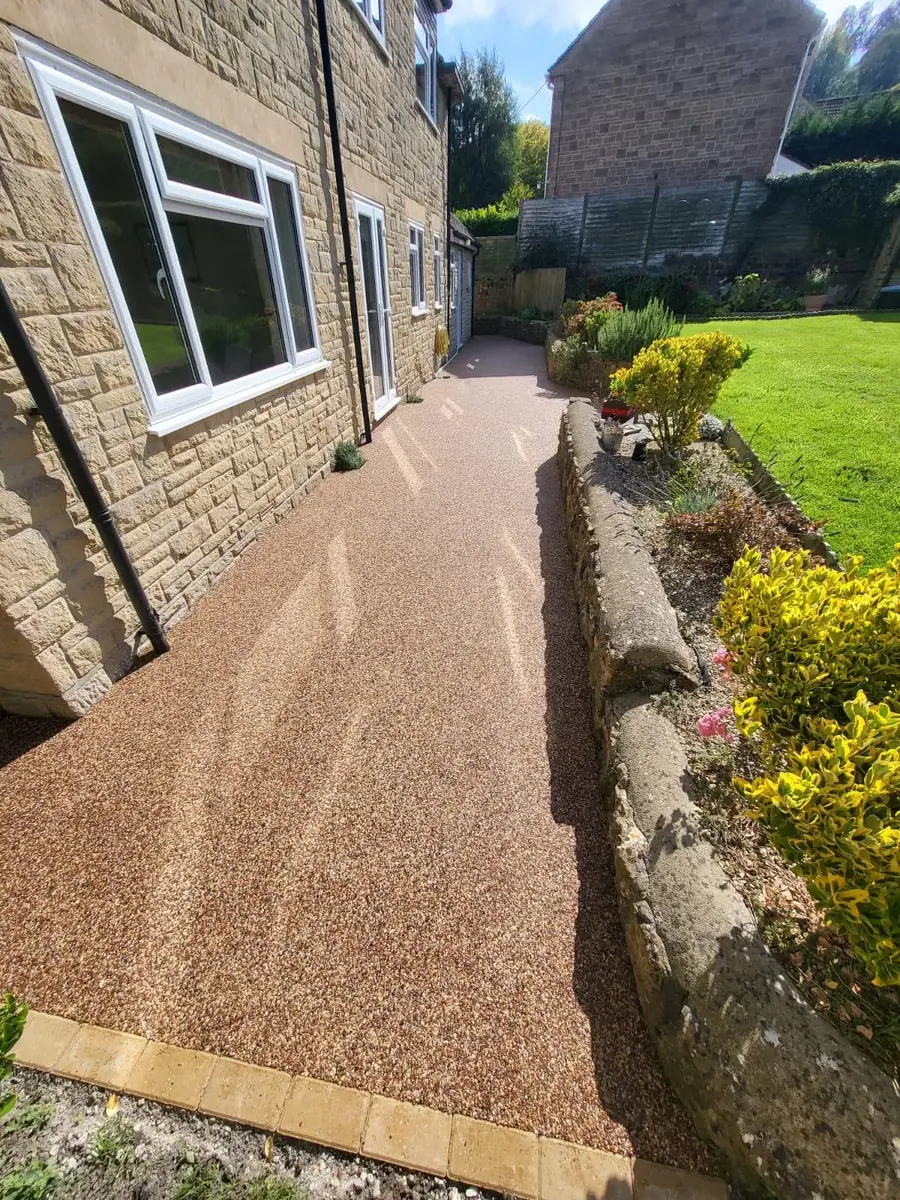 Warm brown resin bound pathway along the side of a stone cottage with garden borders in Bournemouth